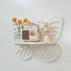 a white butterfly shaped shelf with a radio and flowers