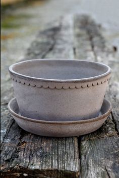 a bowl and saucer sitting on top of a wooden table next to each other