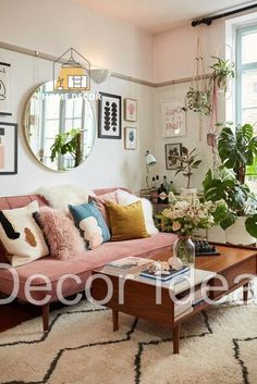 a living room filled with lots of furniture and plants on the wall above it's coffee table