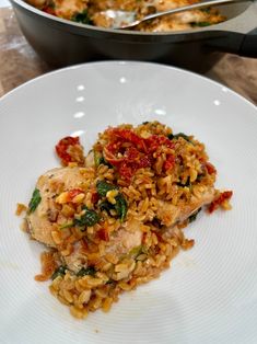 a white plate topped with rice and meat next to a skillet filled with vegetables