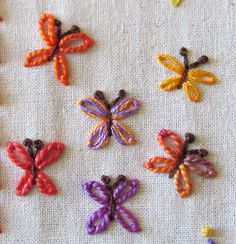 six different colored butterflies on a white cloth covered with thread and crochet work