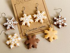 four snowflake shaped cookies are displayed on a card with earwires and earrings