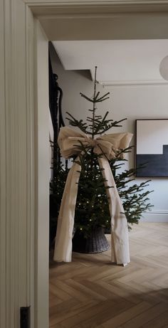 a decorated christmas tree in the corner of a room with white walls and wood flooring