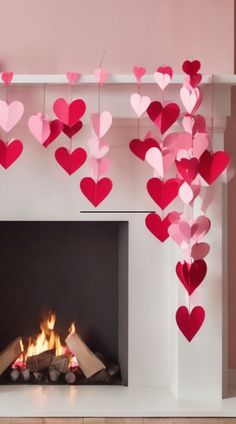 valentine's day decorations hanging over a fireplace with paper hearts on the mantel