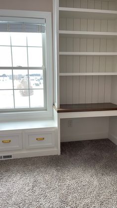 an empty room with white bookcases and drawers