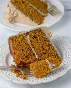 two slices of carrot cake on white plates with a fork in the foreground and one slice missing