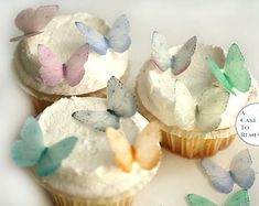 four cupcakes with frosting and butterflies on them are sitting next to each other