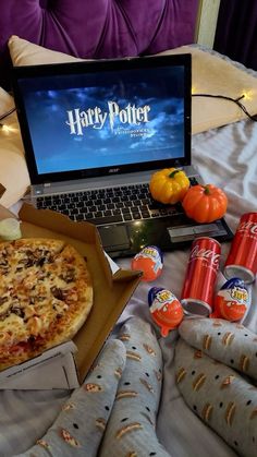 a laptop computer sitting on top of a bed next to pizza and orange juices