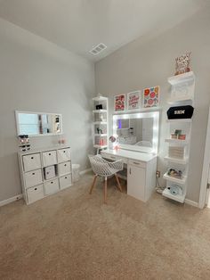 a white desk sitting in the middle of a room with lots of shelves and drawers