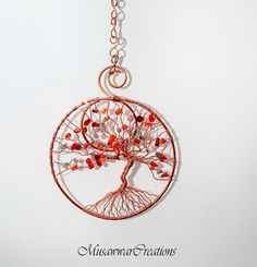 a wire tree pendant with red beads hanging from it's center circle, on a white background