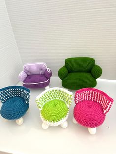 four crocheted baskets sitting on top of a white table next to a green couch