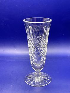 a clear glass vase sitting on top of a blue tableclothed surface with an intricate design