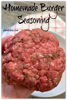 a close up of a person holding a hamburger in their hand with the words homemade burger seasoning on it