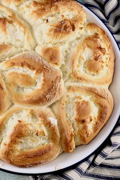 a white plate topped with bread rolls on top of a blue and white table cloth