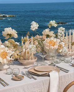 the table is set with flowers and candles on it, along with other place settings