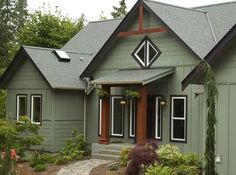 a green house with red trim on the front door and two windows in the back