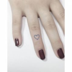 a person with a heart tattoo on their left ring finger and the other hand has a small blue heart tattooed on it