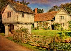 an old house with a fence in front of it and flowers growing on the side