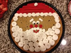 a cake decorated to look like santa clause with white frosting on top and strawberries in the background