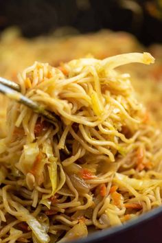 a spoon full of noodles and vegetables being stirred