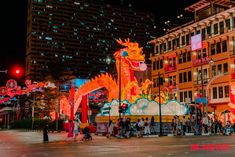 people are walking around in the street at night with brightly lit buildings and dragon decorations