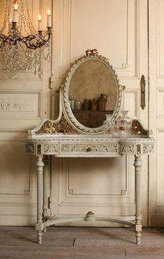 an antique vanity with a mirror and chandelier