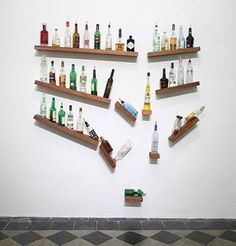 several shelves filled with liquor bottles on top of each other in front of a white wall