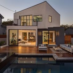 a house with a pool in front of it at dusk, as seen from the backyard