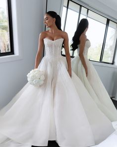 a woman in a wedding dress is looking at herself in the mirror