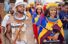 a group of people walking down a street next to each other wearing costumes and headgear