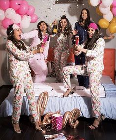 a group of women standing on top of a bed next to each other in pajamas