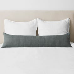 a white bed with two pillows on top of it