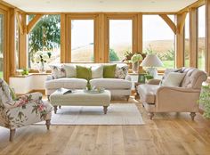 a living room filled with lots of furniture next to tall wooden walls and windows covered in wood beams