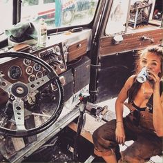 a woman sitting in the driver's seat of a truck drinking from a can