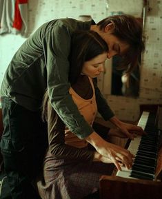 a man and woman are playing the piano together