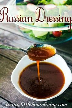 russian dressing being poured into a bowl with salad in the background