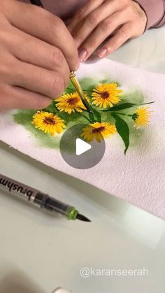 someone is painting flowers on a piece of paper