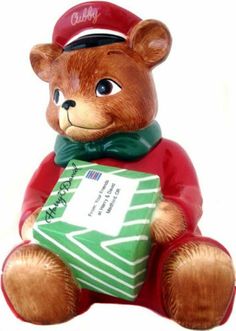 a brown teddy bear holding a green box with writing on it's face and wearing a sailor hat