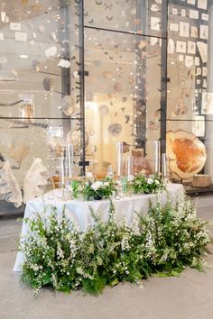 the table is set up with white flowers and greenery for an elegant wedding reception