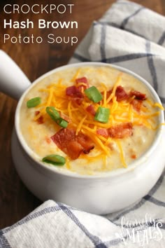 a white bowl filled with potato soup on top of a wooden table next to a spoon