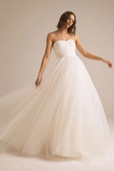 a woman in a white wedding dress posing for the camera with her hand on her hip