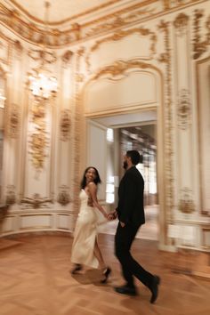 a man and woman are walking in an ornate room