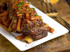 a white plate topped with meat and veggies on top of a wooden table