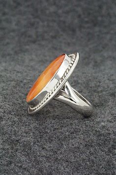 two silver rings with an orange stone in the center on a gray surface, close up