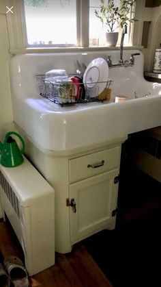 a white sink sitting under a window next to a green pot and pan on top of a counter