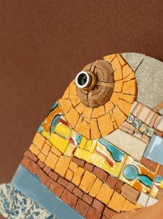 a close up of a bird made out of mosaic tiles and wood with an eye on it's face