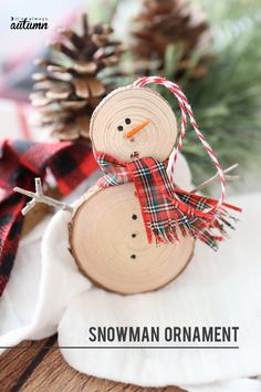 a snowman ornament made out of wood is sitting on a table with pine cones