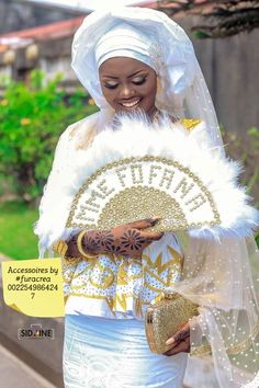 a woman dressed in white and gold holding a fan with the word beautiful written on it