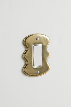 a single light switch cover in gold on a white wall