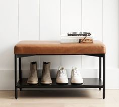 four pairs of shoes are lined up on a bench in front of a white wall